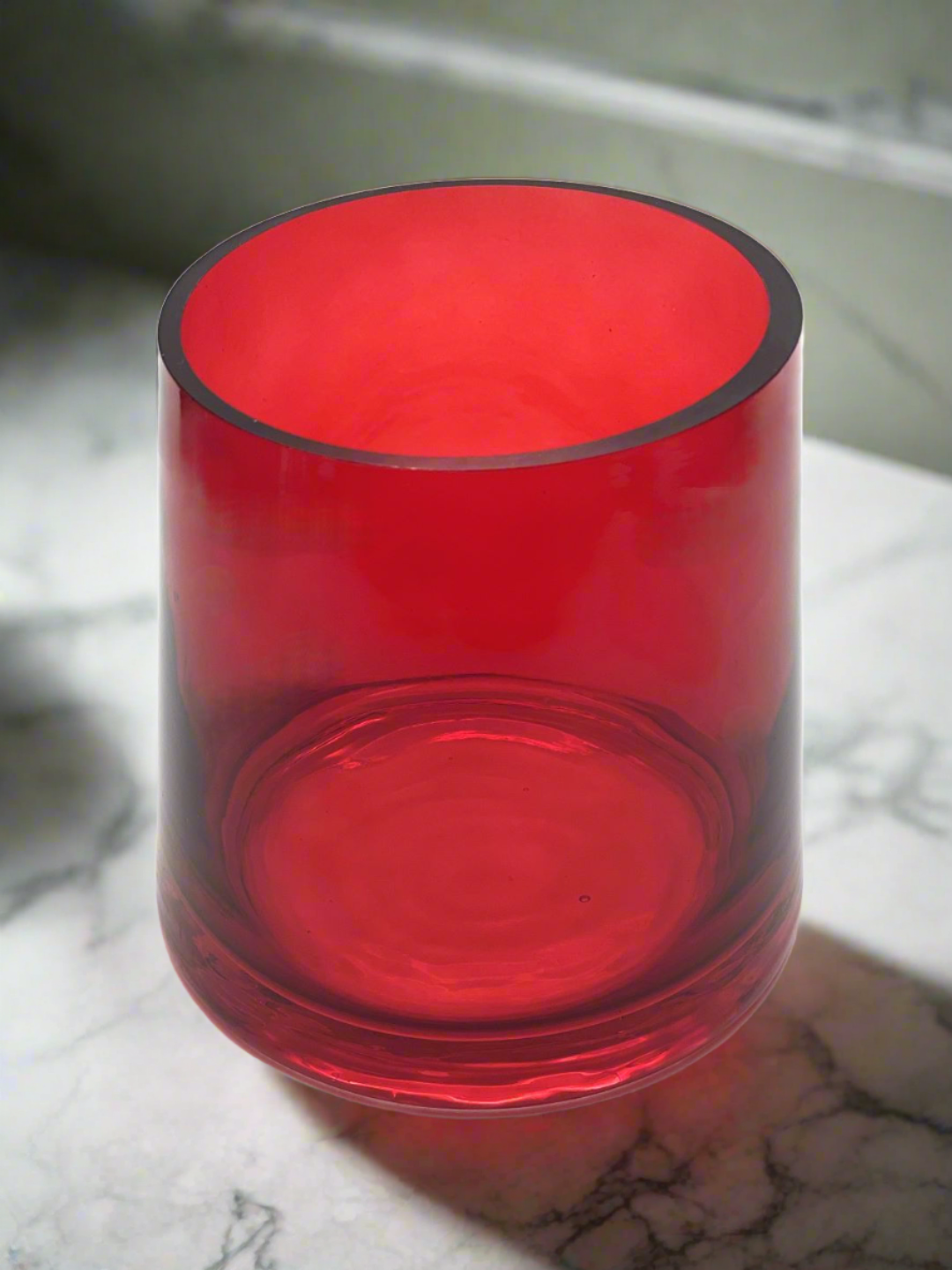 Red hand blown flared glass vase top view on marble background