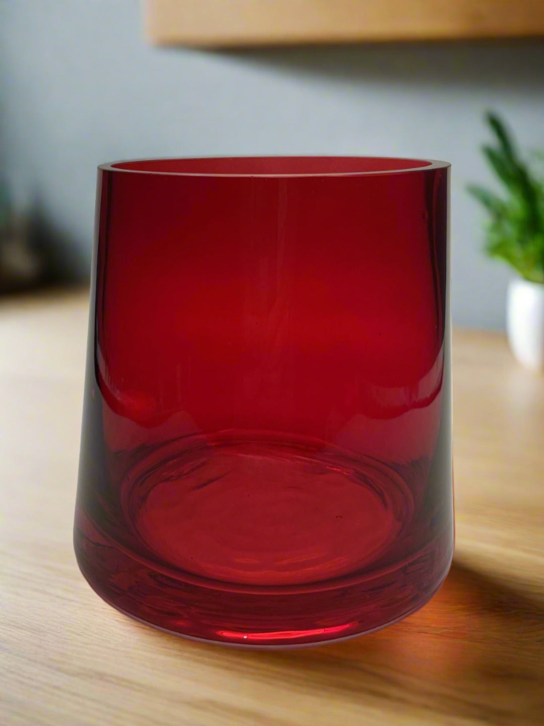 Red hand blown flared glass vase with background scene