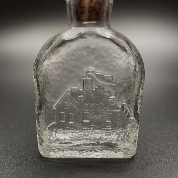 Vintage-bottle-with-embosed-log-cabin-design-closeup-view-Its-A-Blast-Glass-Tucson