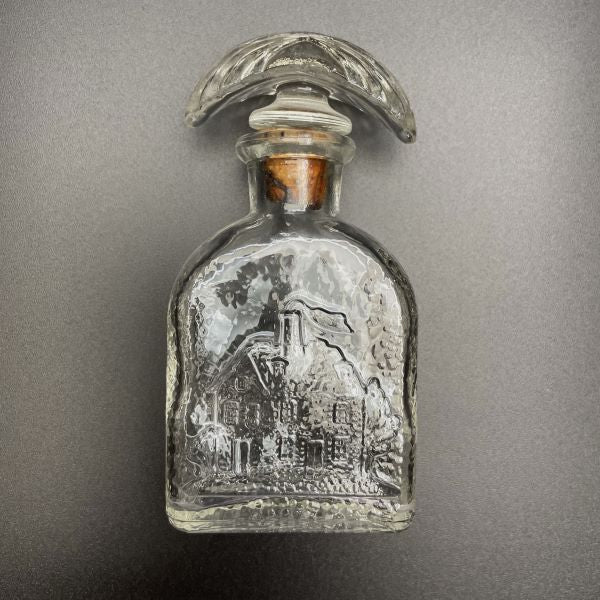 Vintage-bottle-with-embosed-log-cabin-design-side-view-Its-A-Blast-Glass-Tucson